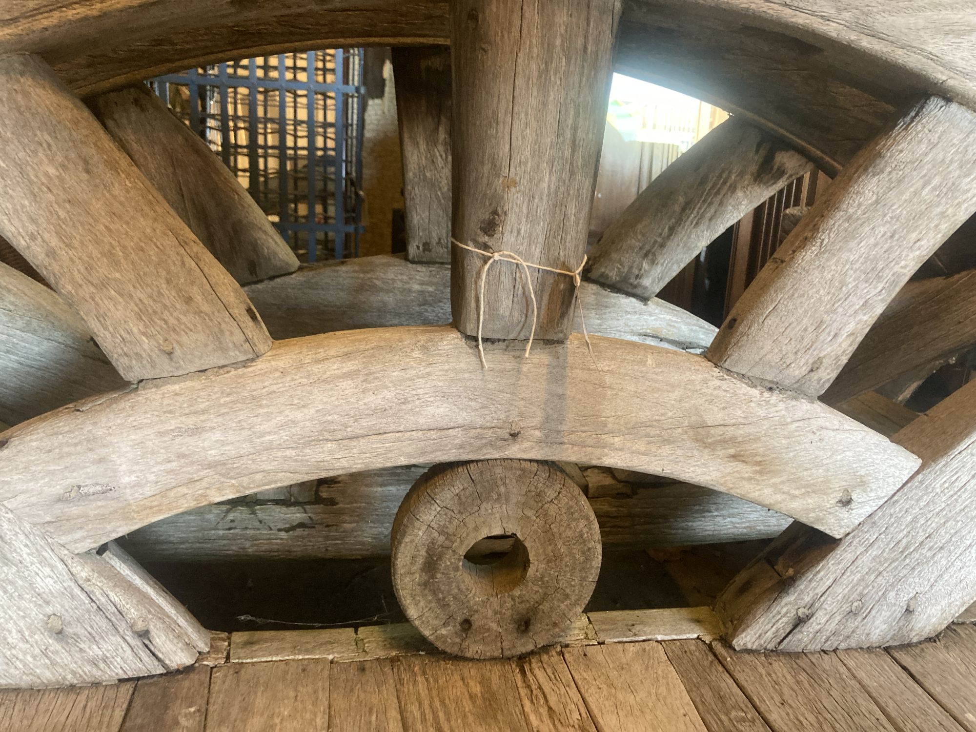 A pair of weathered hardwood cartwheel and hub garden benches, width 184cm depth 75cm height 105cm